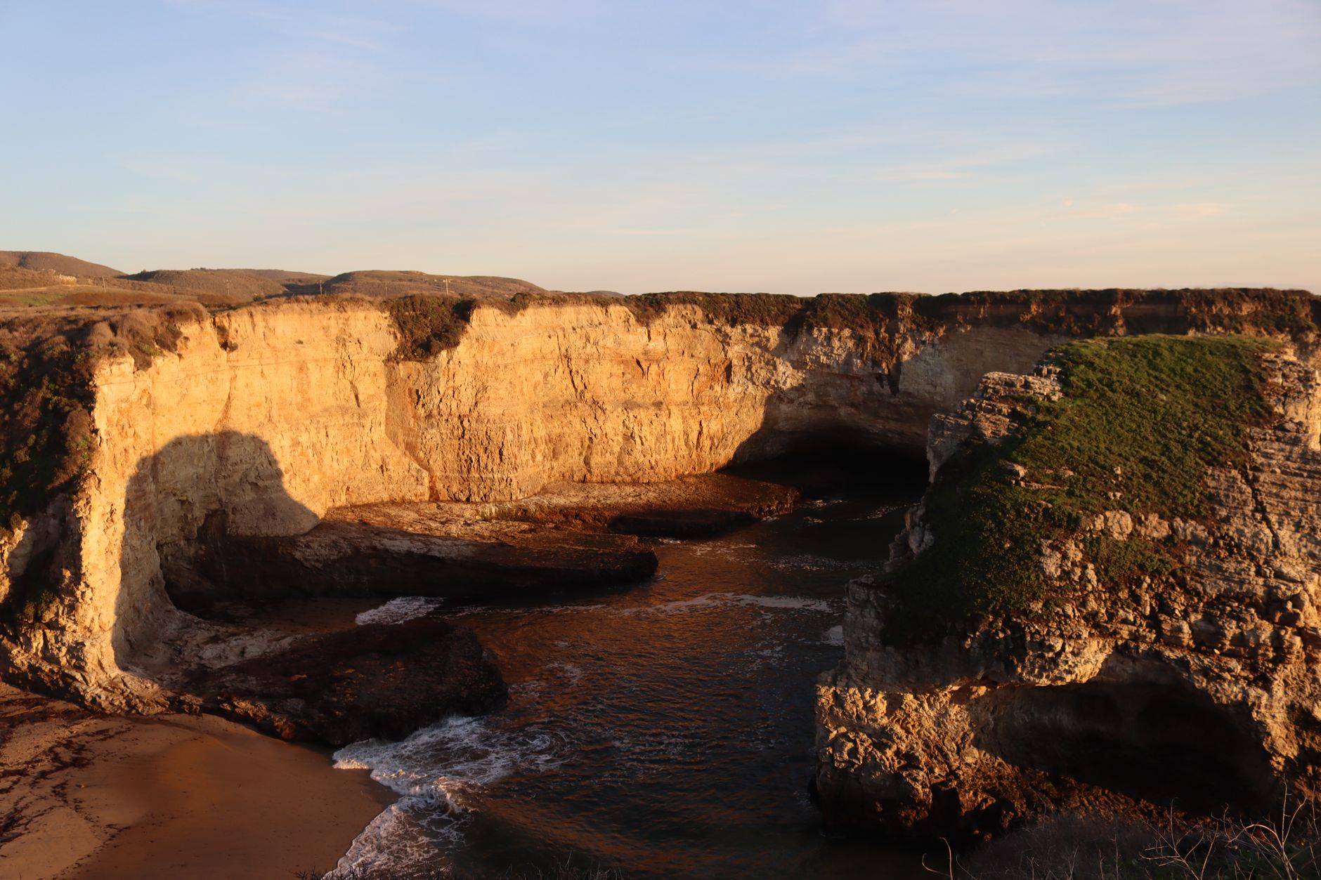 Explore majestic eroded coastal cliffs at sunset with vibrant sea and rocky shore.